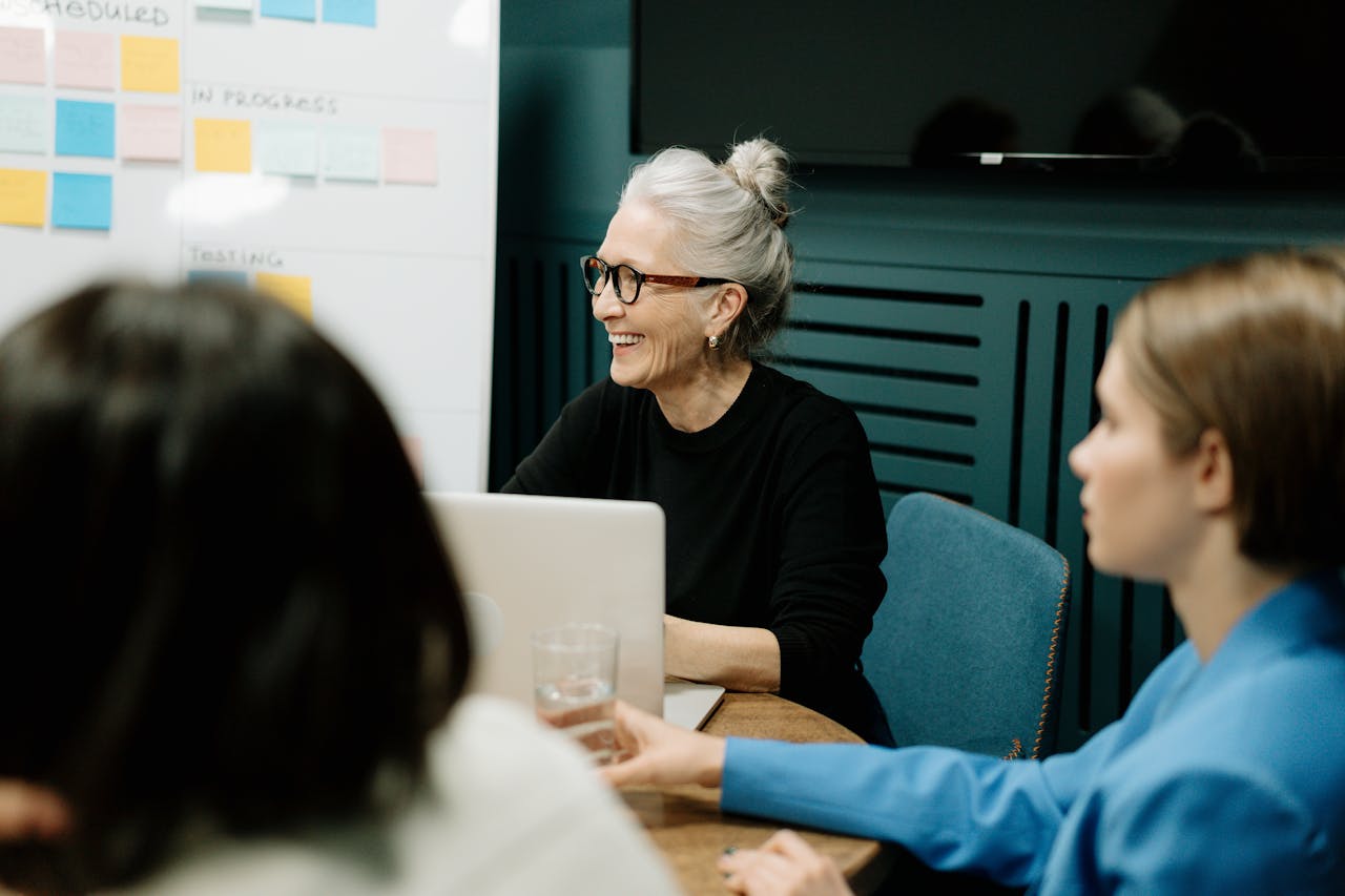 our-story Smiling senior businesswoman leading a diverse team meeting in an office.